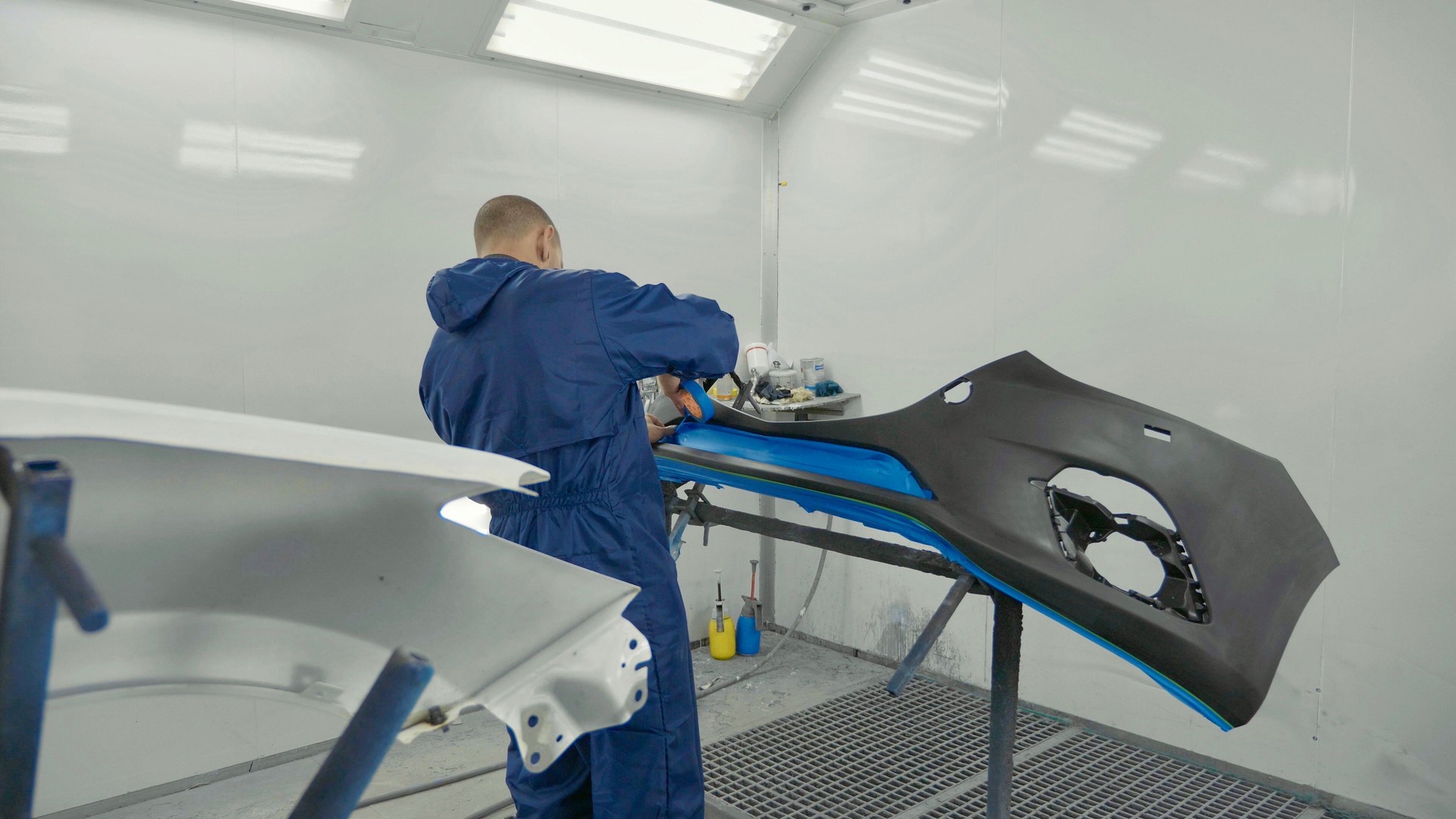 Serviceman preparing a car bodykit for painting in a workshop